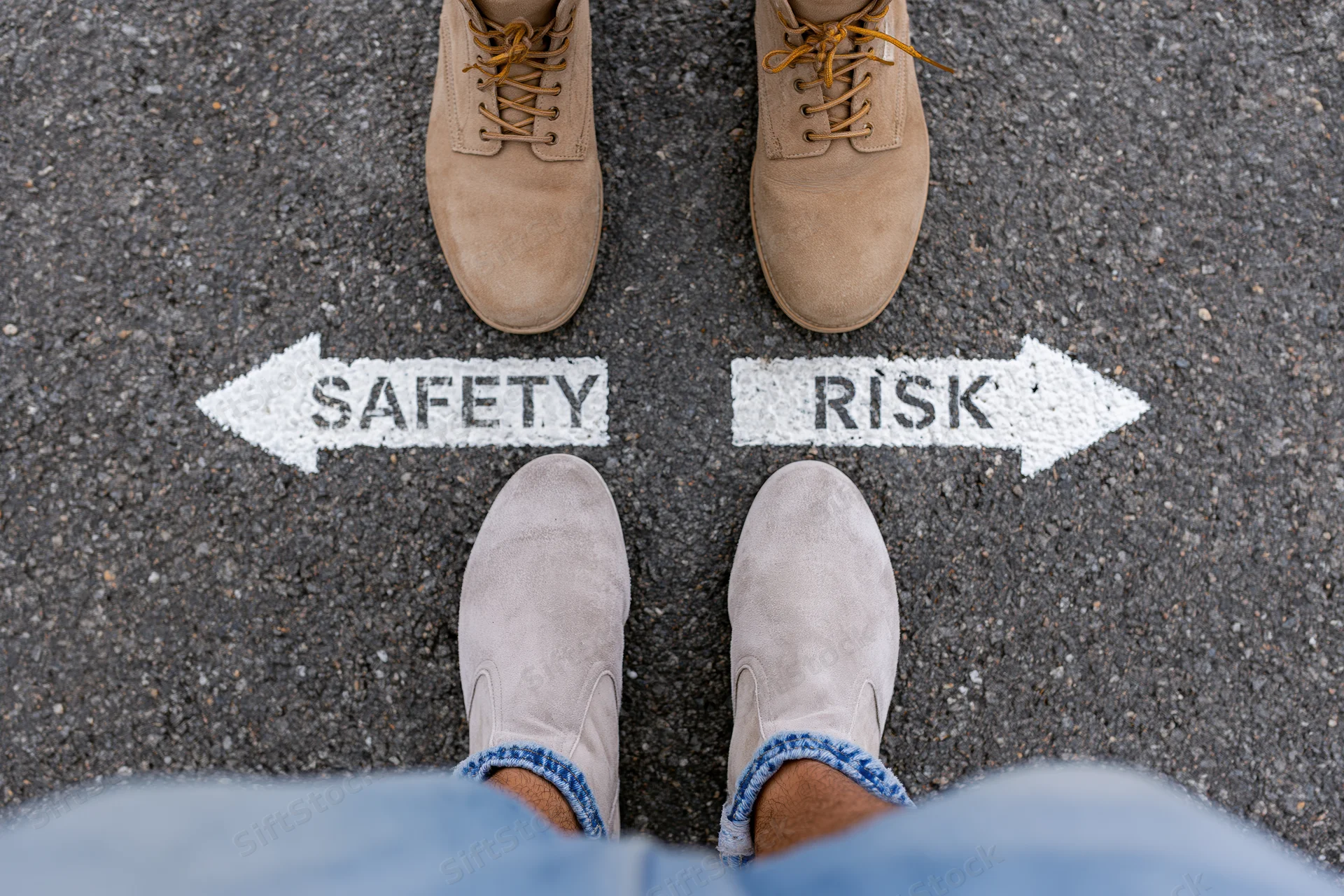 Person standing at crossroads with safety and risk arrows painted on asphalt pavement