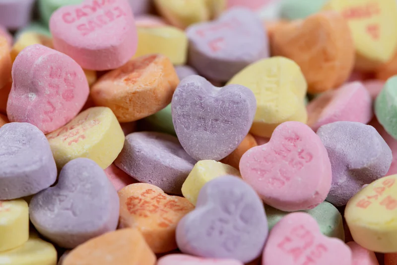 Pile of pastel heart-shaped candies with embossed messages scattered together