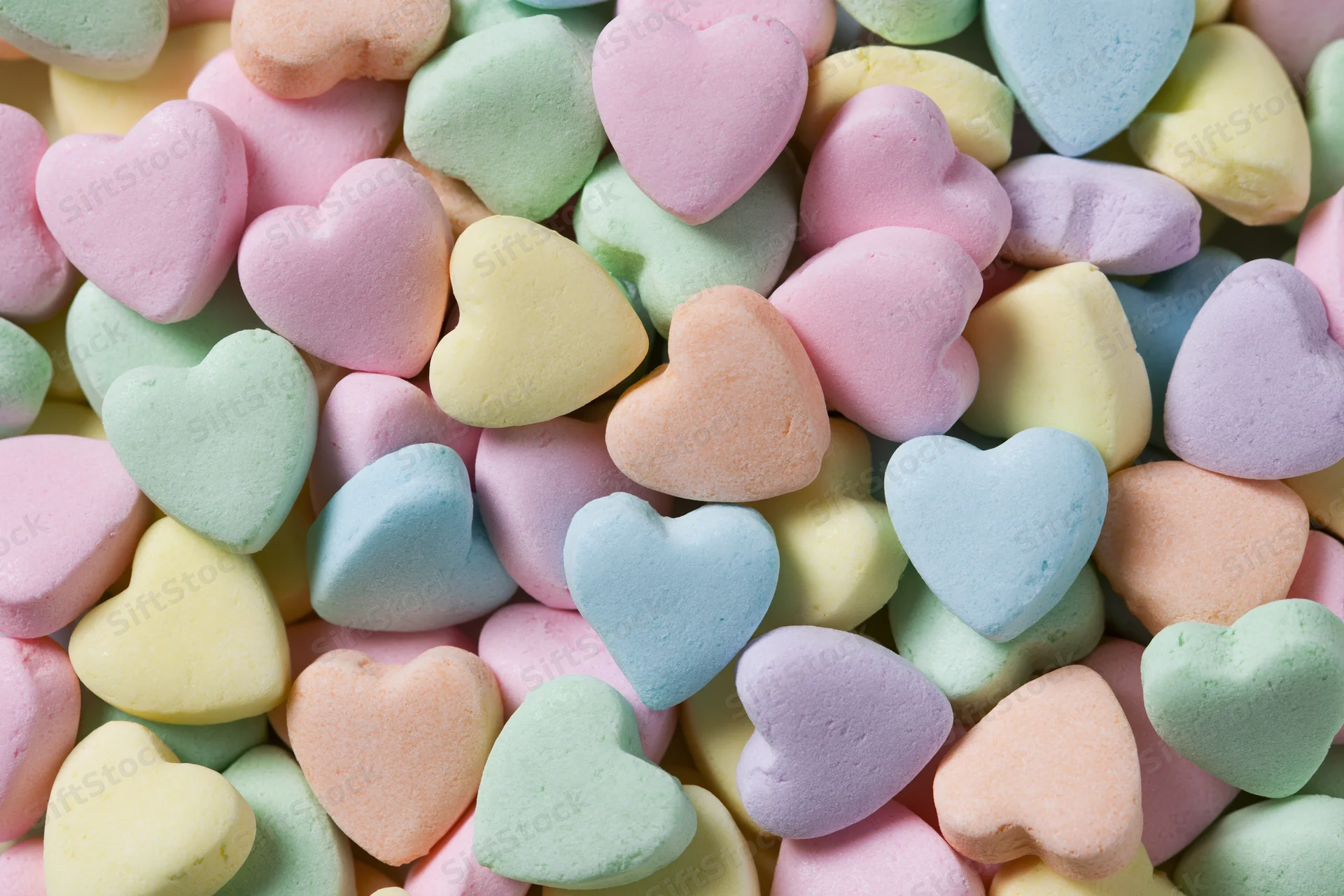 Pile of pastel heart-shaped candies filling the frame