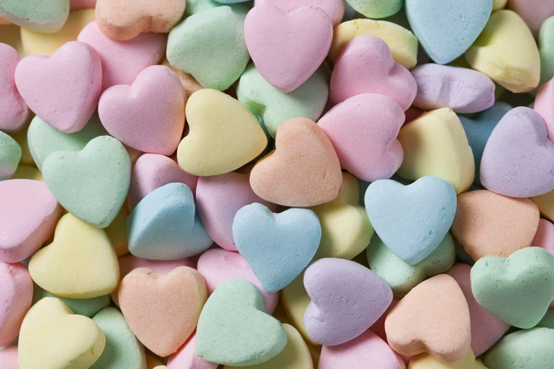 Pile of pastel heart-shaped candies filling the frame