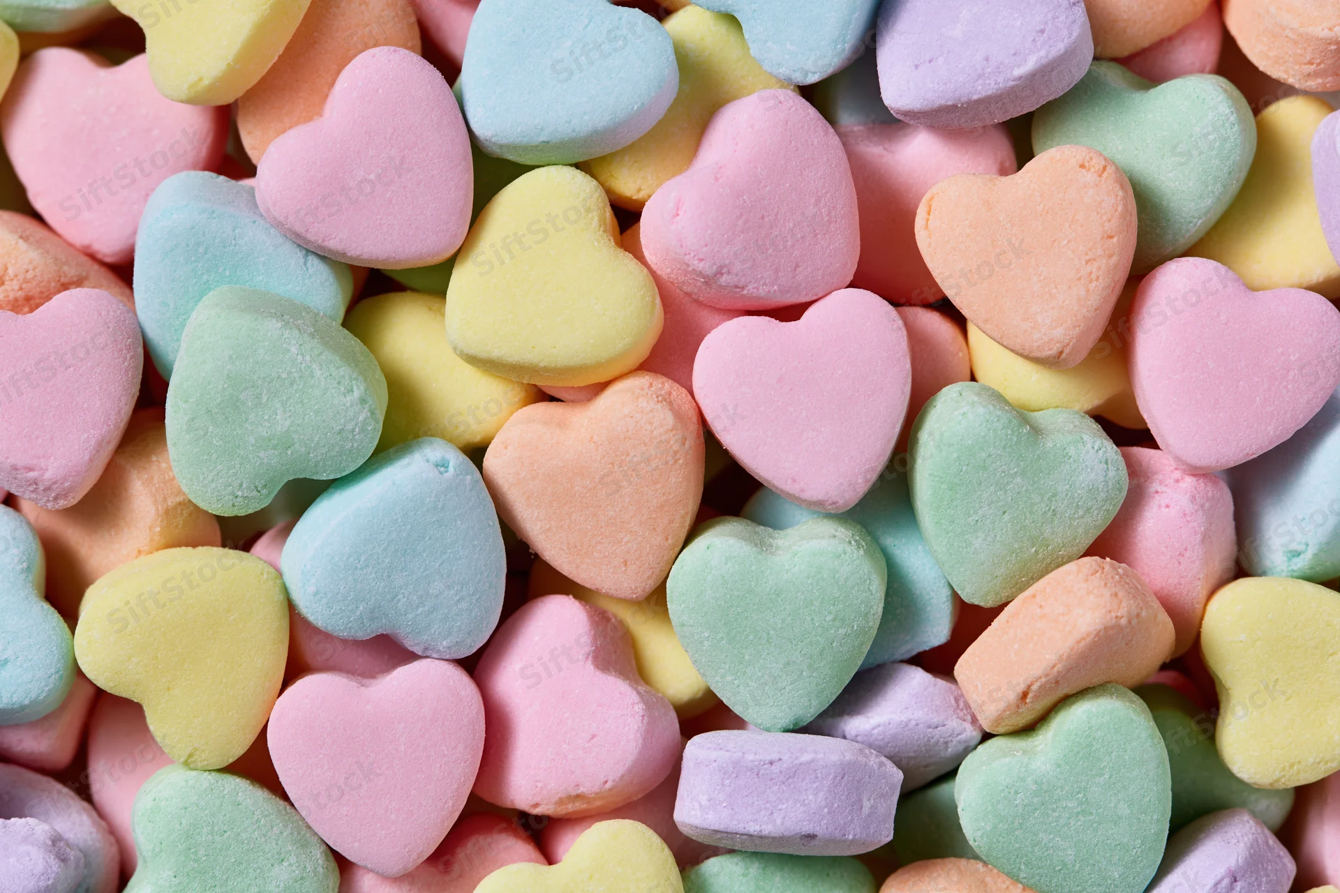 Pile of pastel heart-shaped candies filling the frame