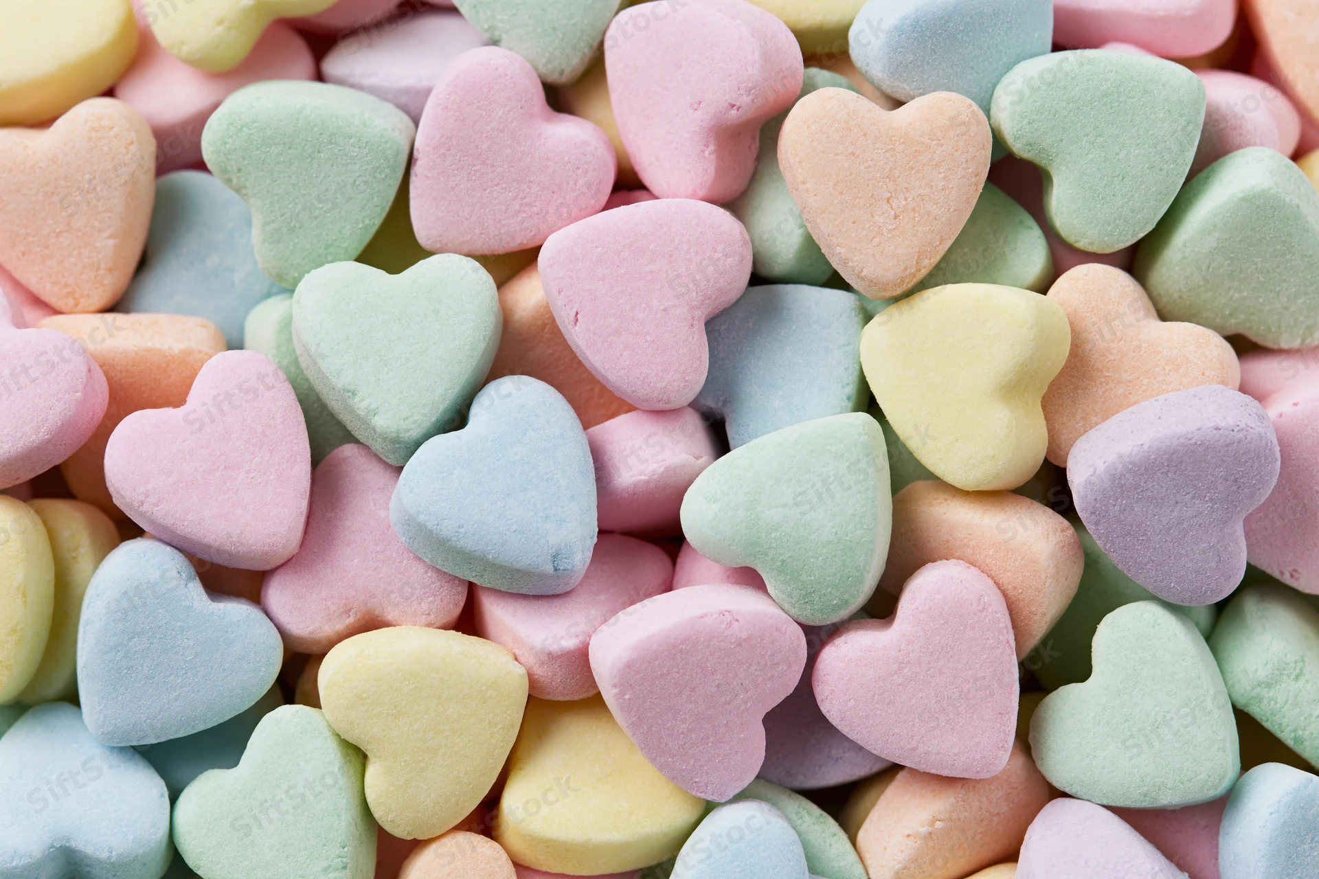 Pile of pastel heart-shaped candies filling the frame