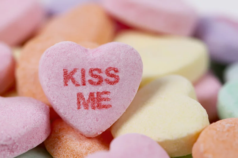 Pink heart-shaped candy with kiss me text among colorful sweets