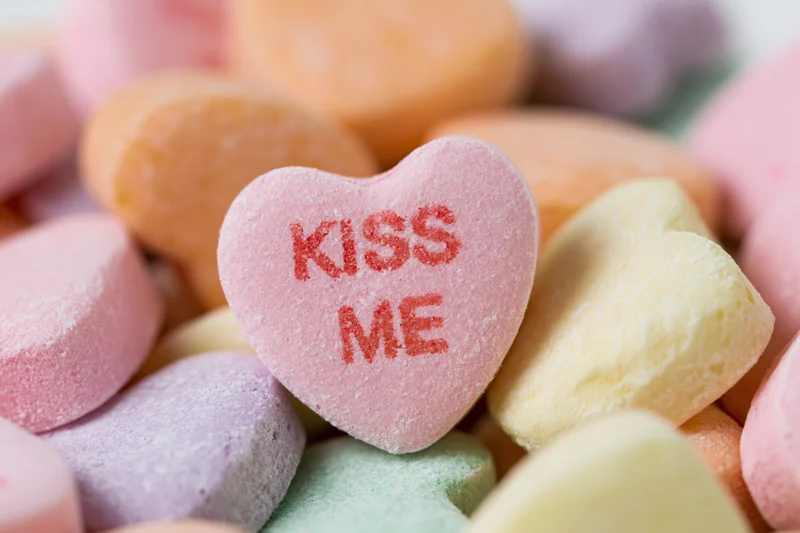 Pink heart-shaped candy with kiss me text among colorful sweets