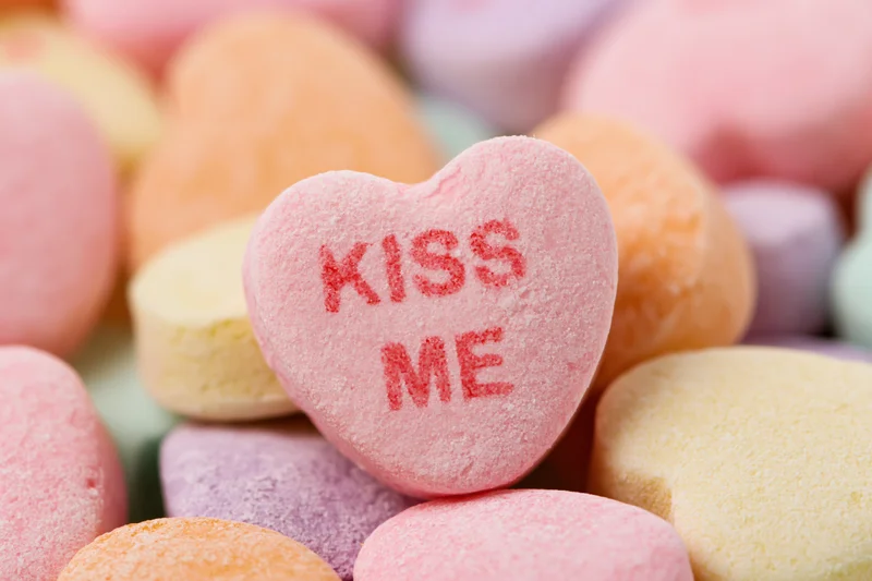 Pink heart-shaped candy with kiss me text among pastel candies