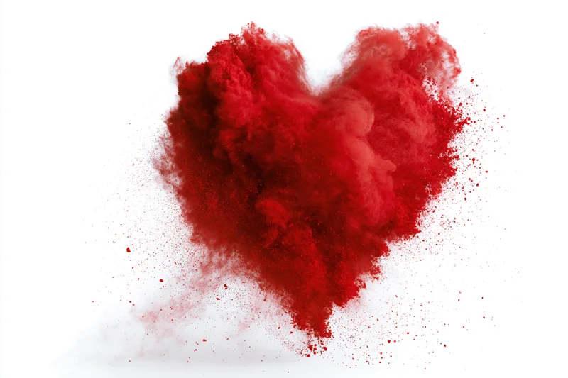 Red powder exploding in heart shape against white background