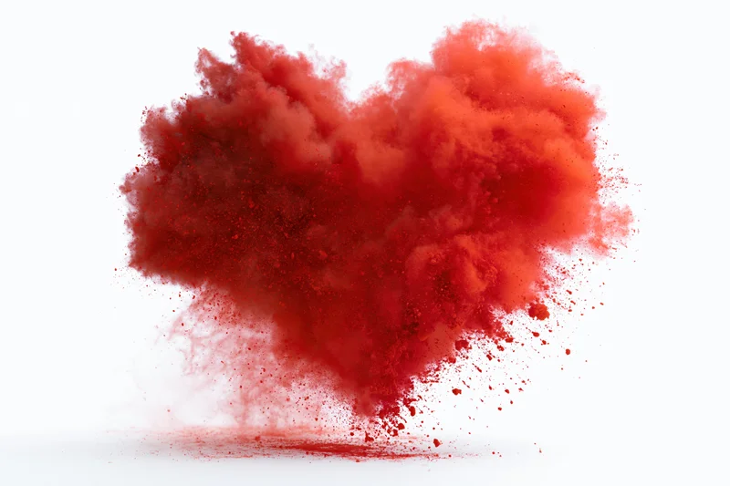 Red powder exploding in heart shape midair against white background