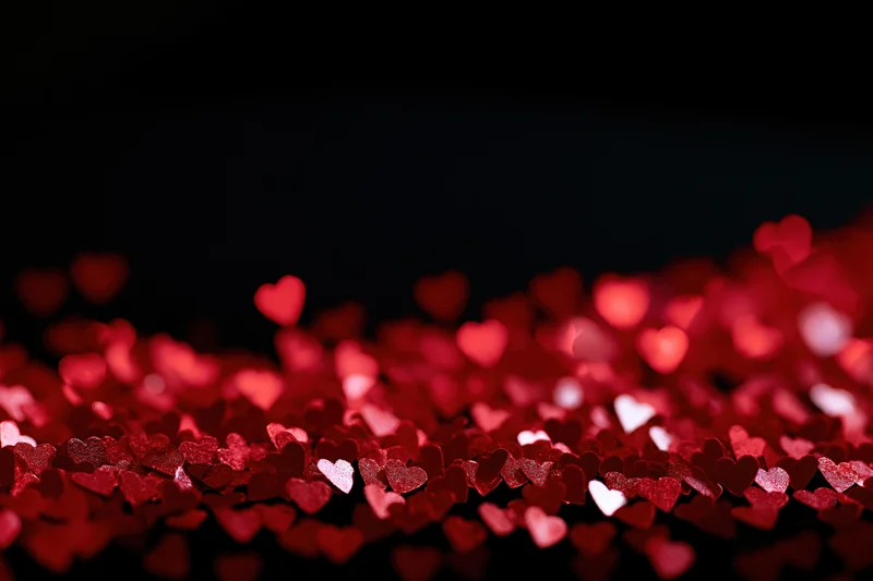 Red heart-shaped bokeh lights scattered across a dark background