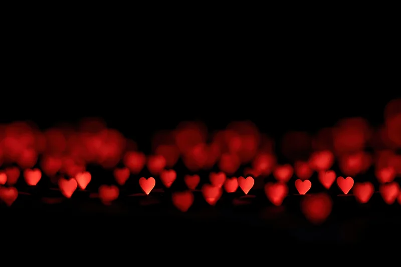 Red heart-shaped bokeh lights scattered across the lower portion of a dark frame