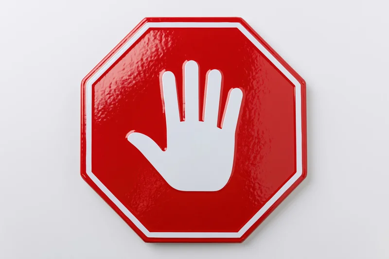 Red octagonal stop sign with white hand symbol on plain background