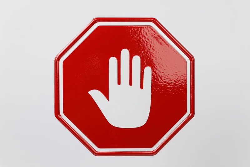 Red octagonal stop sign with white hand symbol on plain background