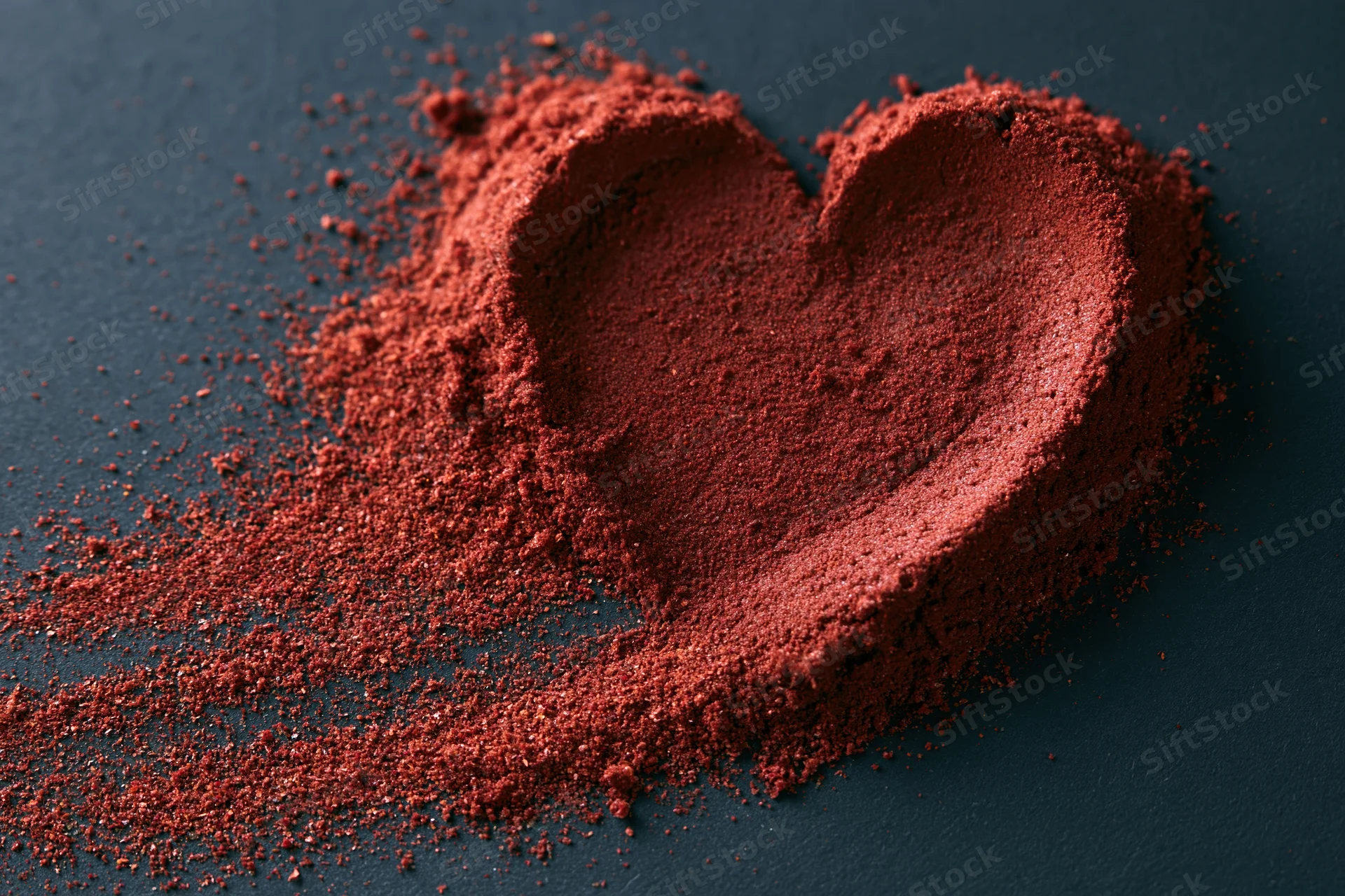 Red powder shaped into a heart on a dark surface