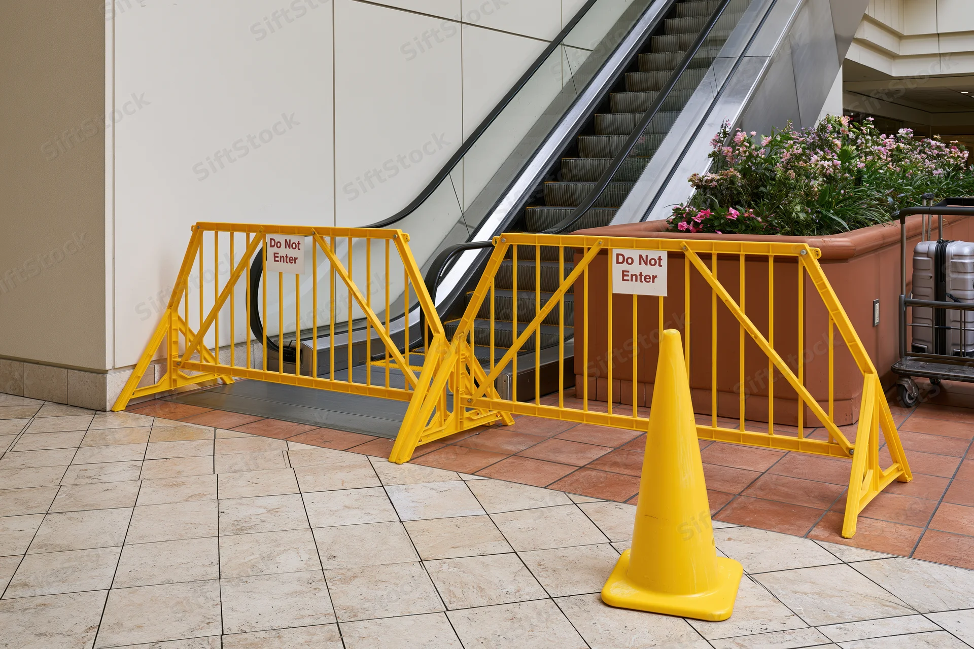 Yellow safety barriers with do not enter signs blocking escalator in shopping mall interior