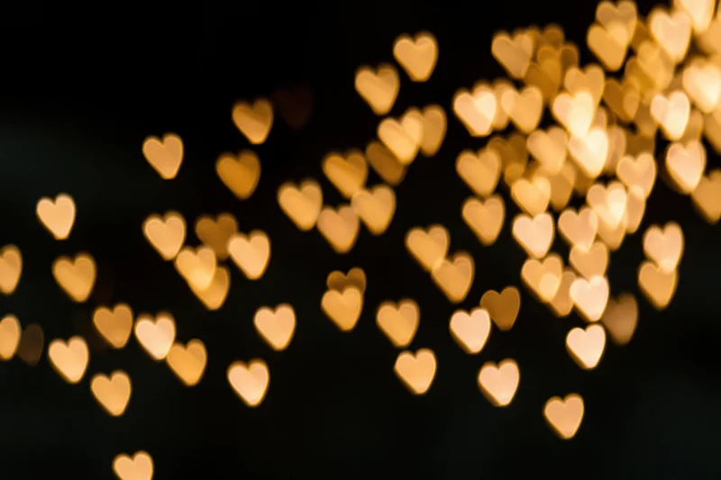 Heart-shaped bokeh lights glowing softly against a dark background