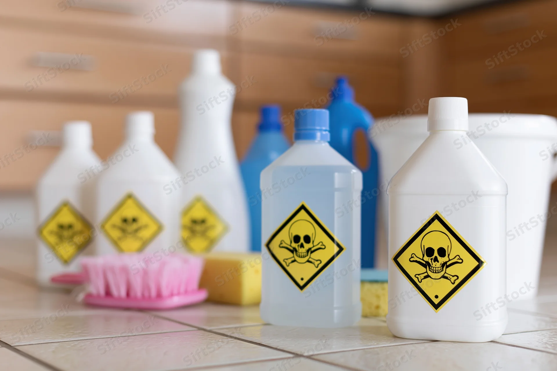 Hazardous cleaning chemicals with skull warning labels arranged on a kitchen countertop