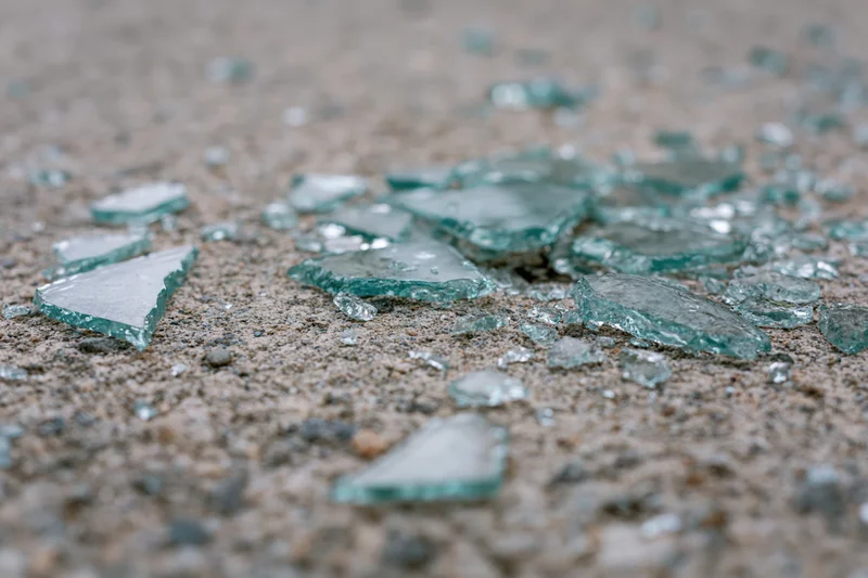 Shattered safety glass scattered across a rough concrete floor