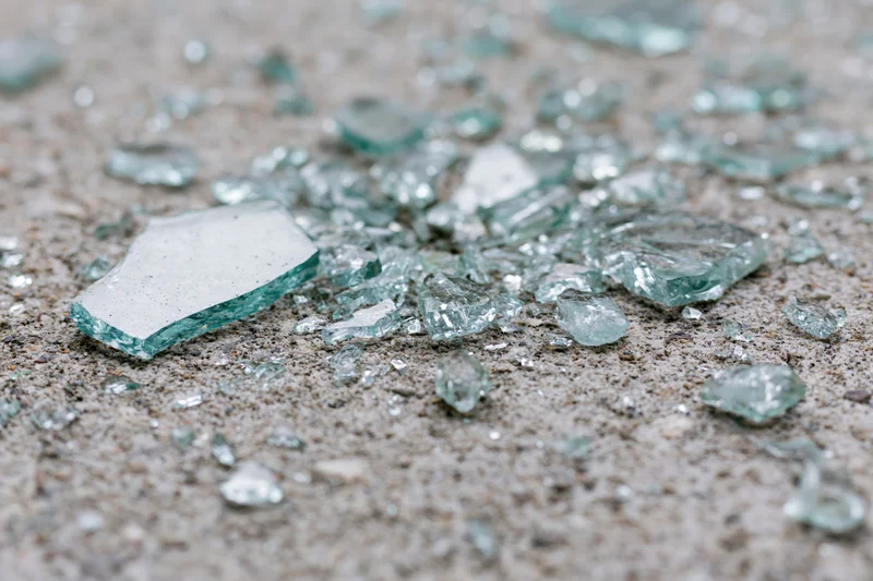Shattered safety glass scattered across a rough concrete floor
