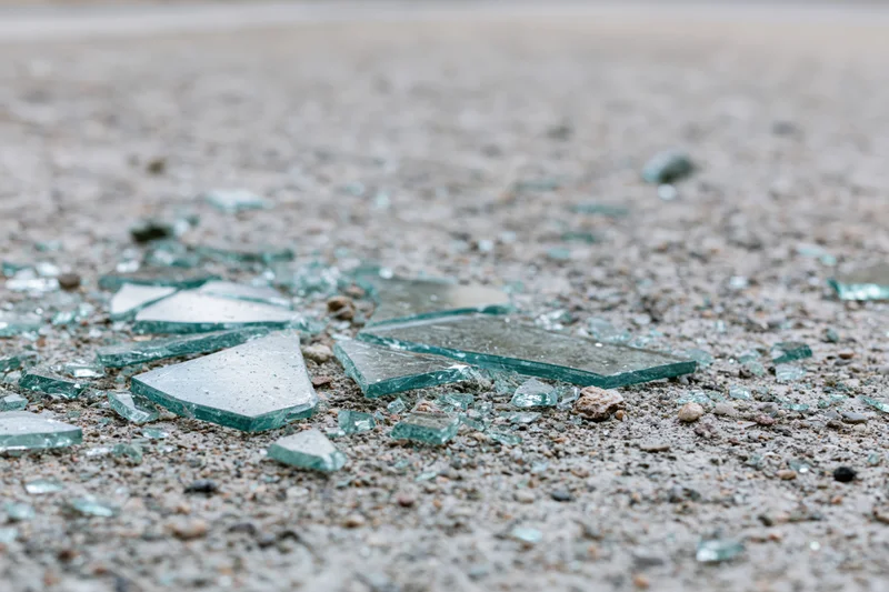 Shattered safety glass scattered across a rough concrete floor