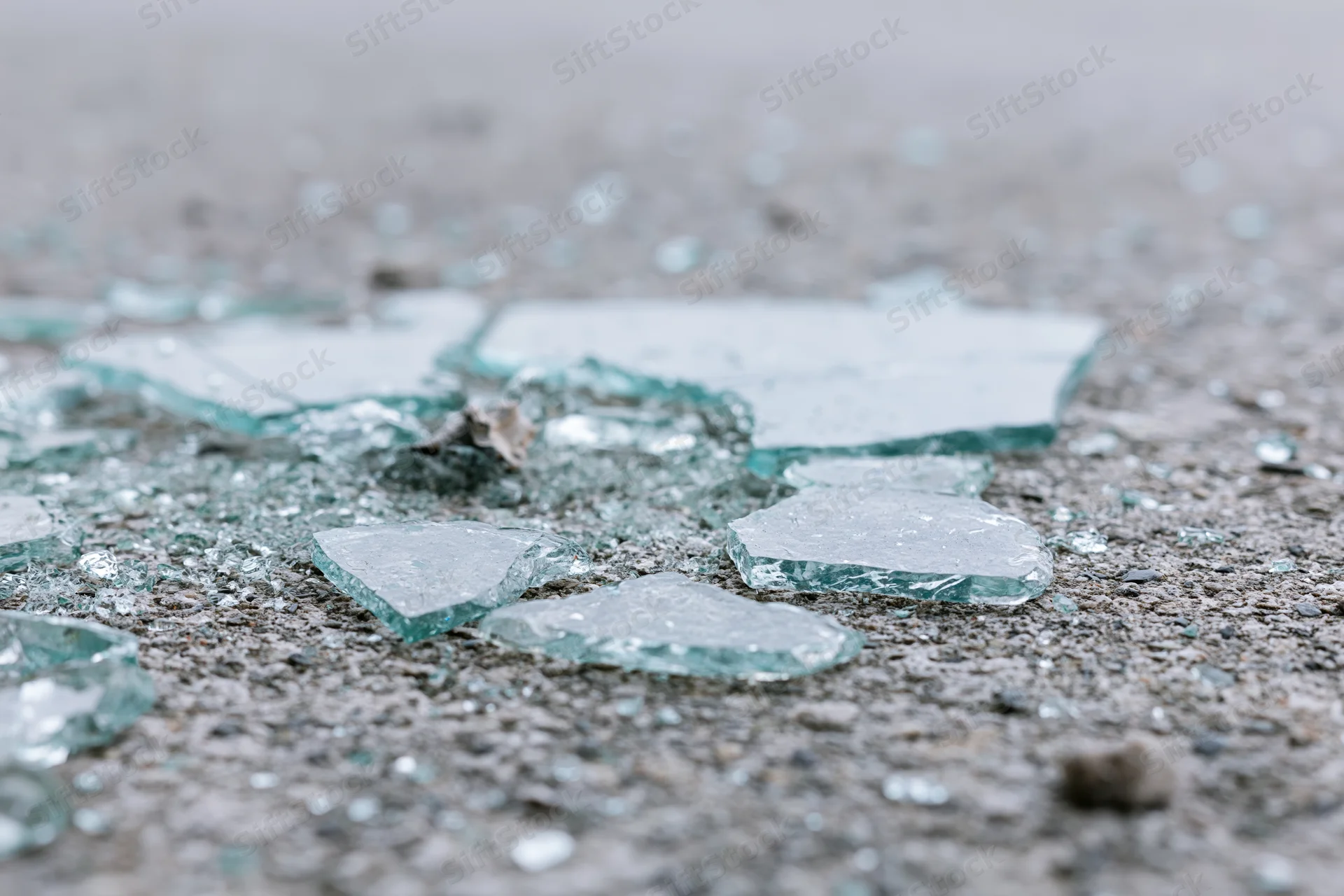 Shattered safety glass scattered across rough concrete floor