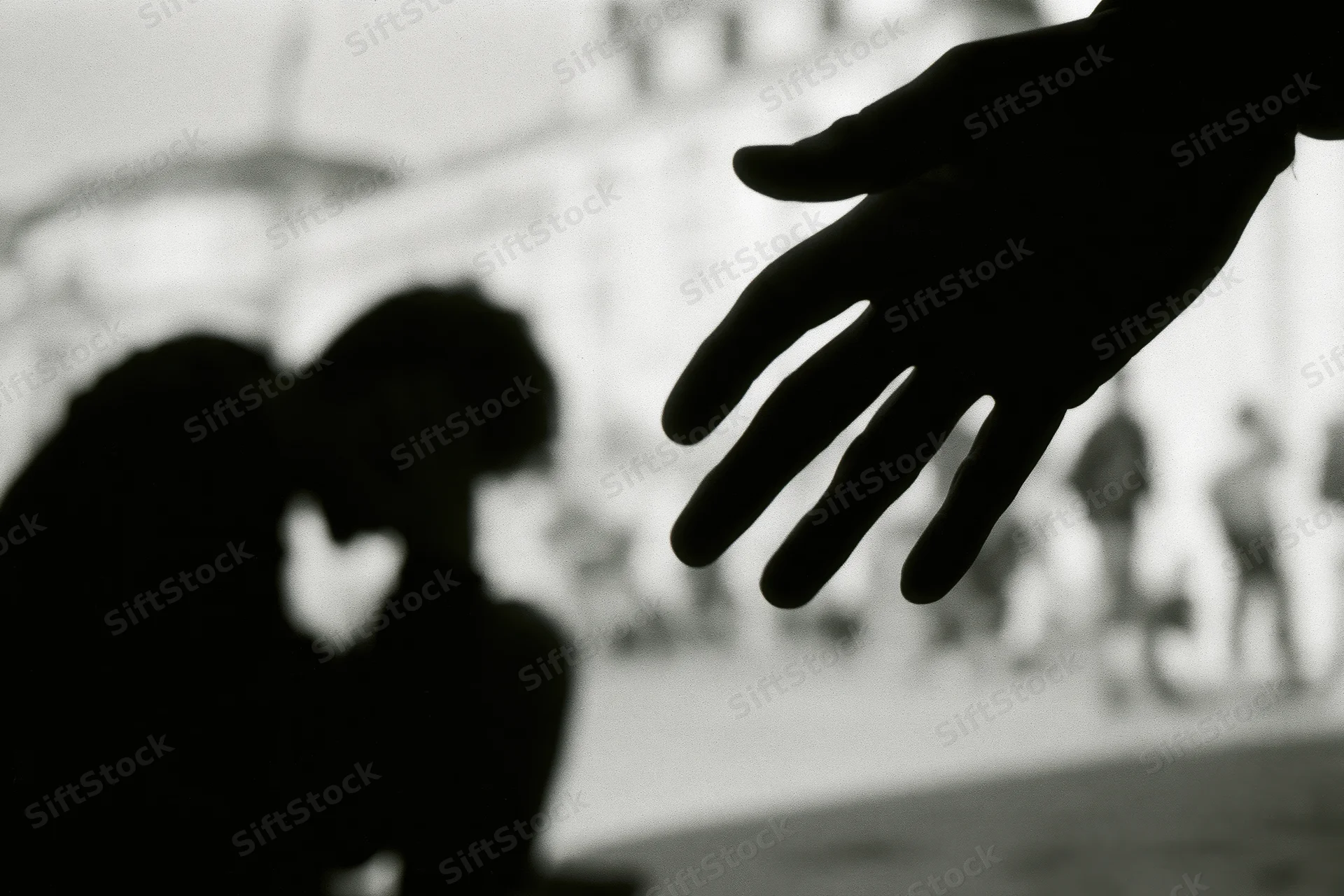Silhouette of a hunched young person with a reaching hand in an urban setting