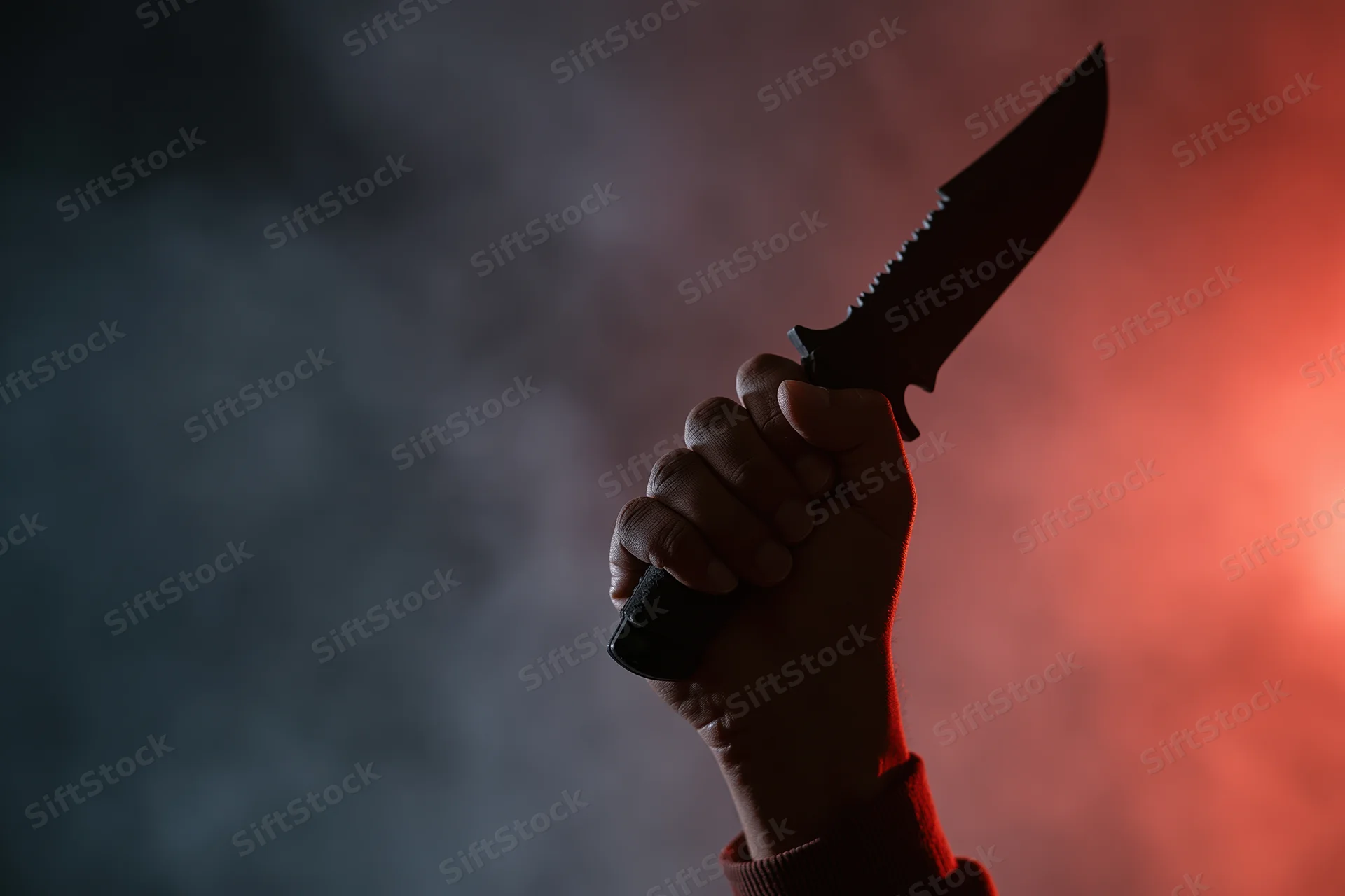 Hand gripping a tactical serrated knife raised against a smoky red and dark background