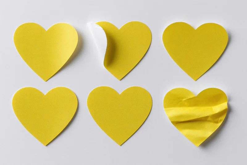Six yellow heart-shaped stickers arranged in two rows on a white surface