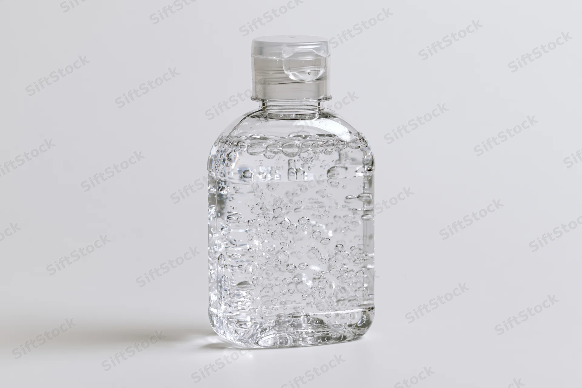 Clear plastic hand sanitizer bottle filled with gel on white surface
