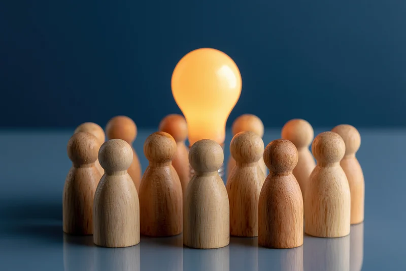 Wooden figures arranged in a circle around a glowing lightbulb on a reflective surface