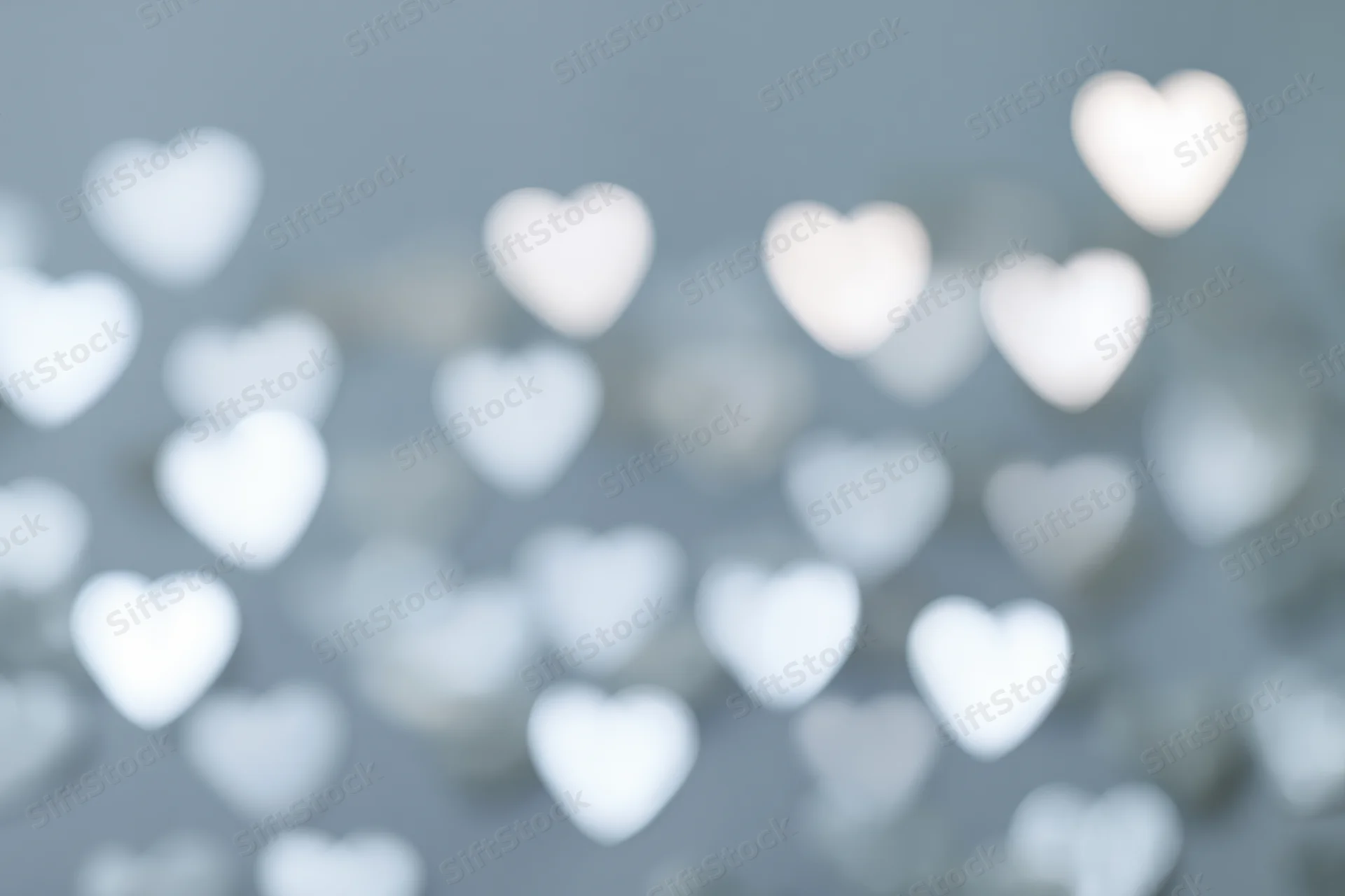 Soft bokeh background with scattered heart-shaped light spots in gray and white tones