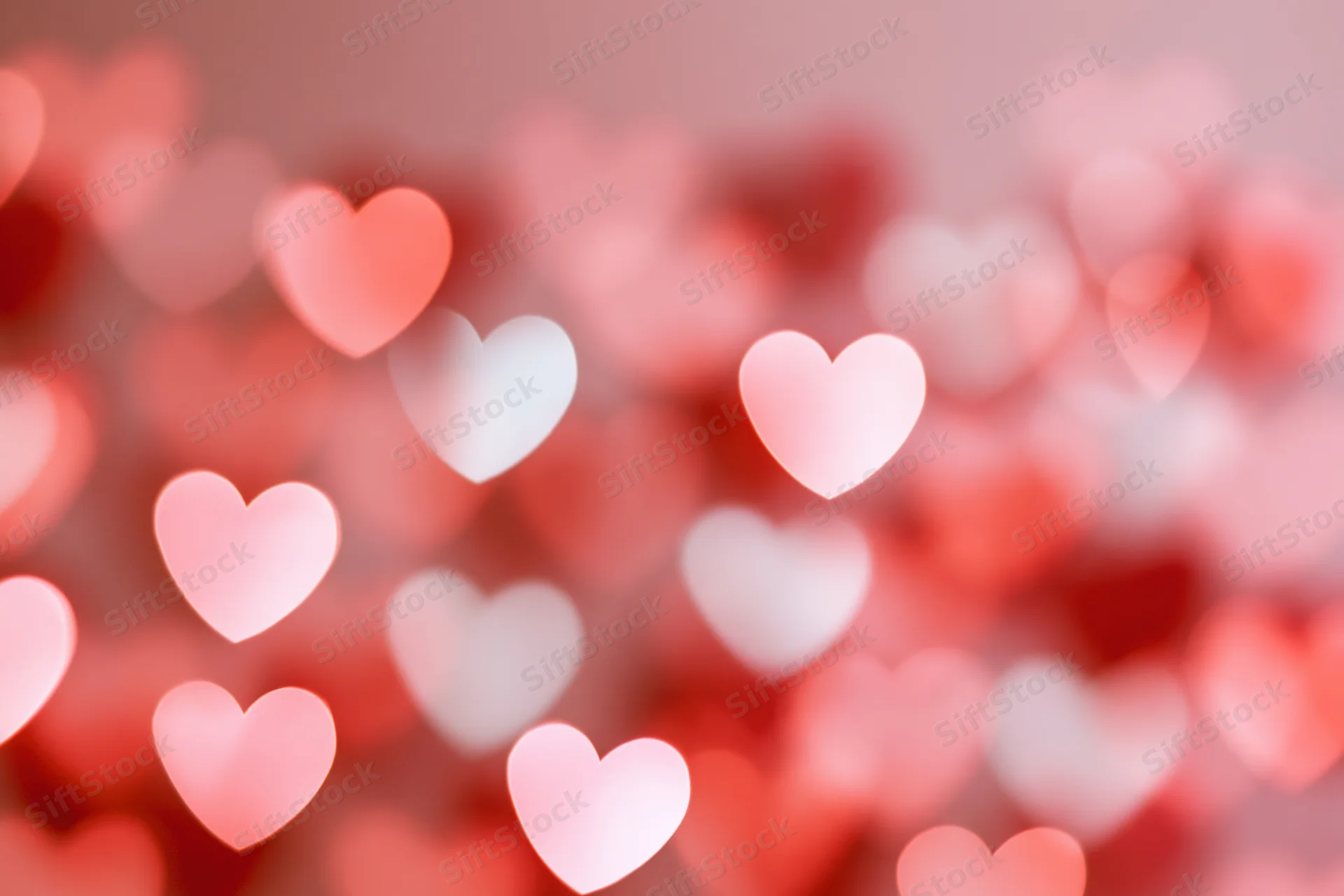 Soft out-of-focus heart-shaped bokeh lights scattered across a pink background