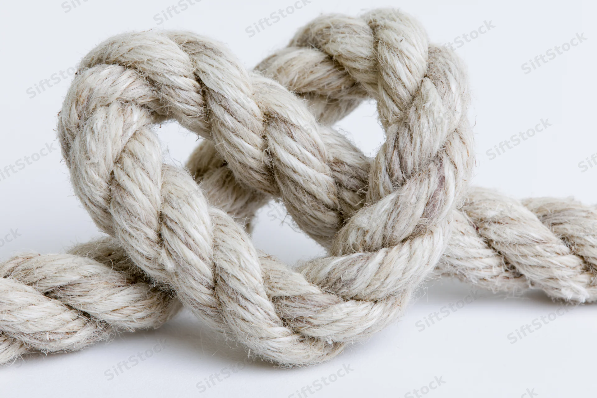 Thick natural fiber rope tied into a heart-shaped knot on a white background