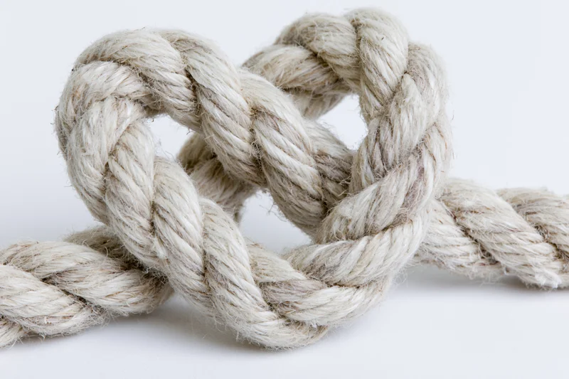 Thick natural fiber rope tied into a heart-shaped knot on a white background