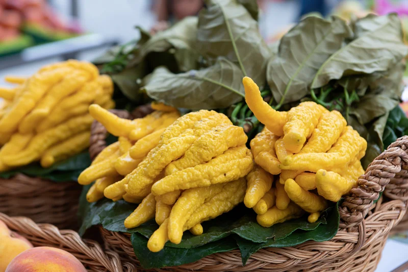 Buddha's-hand citrus fruits in woven baskets with green leaves at a market stall