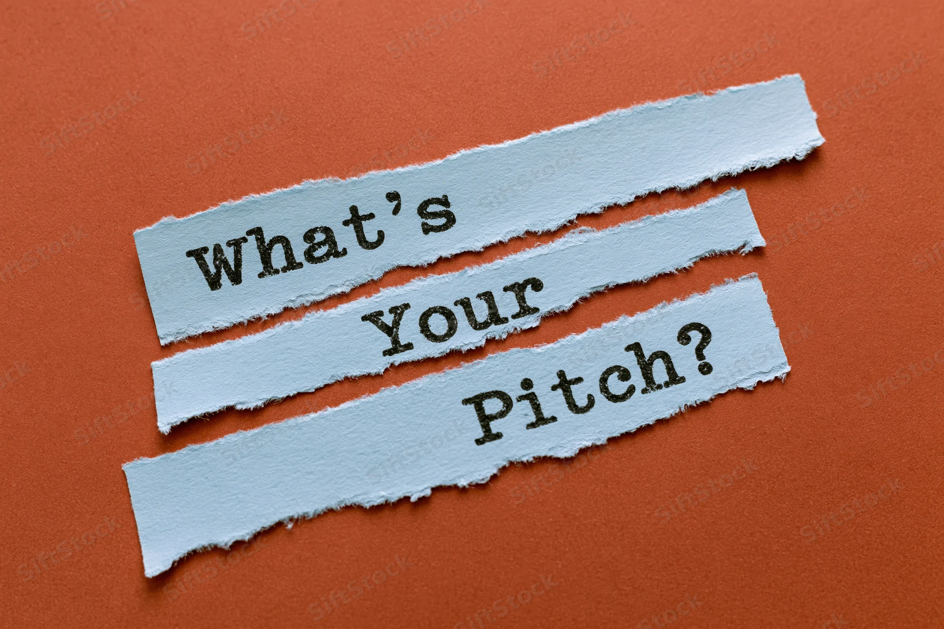 Torn blue paper strips with text what's your pitch arranged diagonally on orange surface