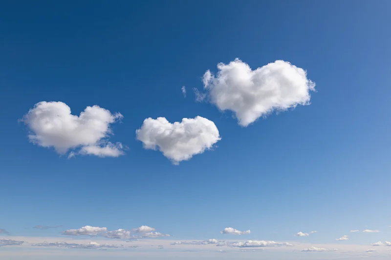 Three heart-shaped clouds floating in a clear blue sky