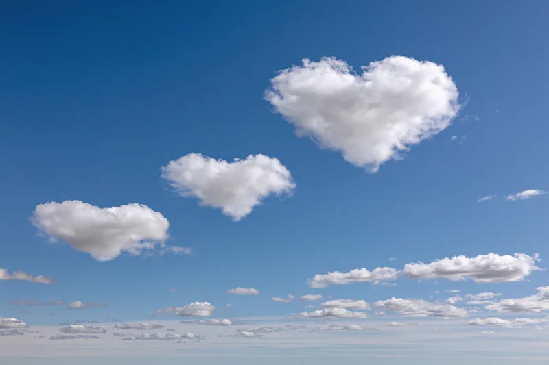 Three heart-shaped clouds floating in a clear blue sky