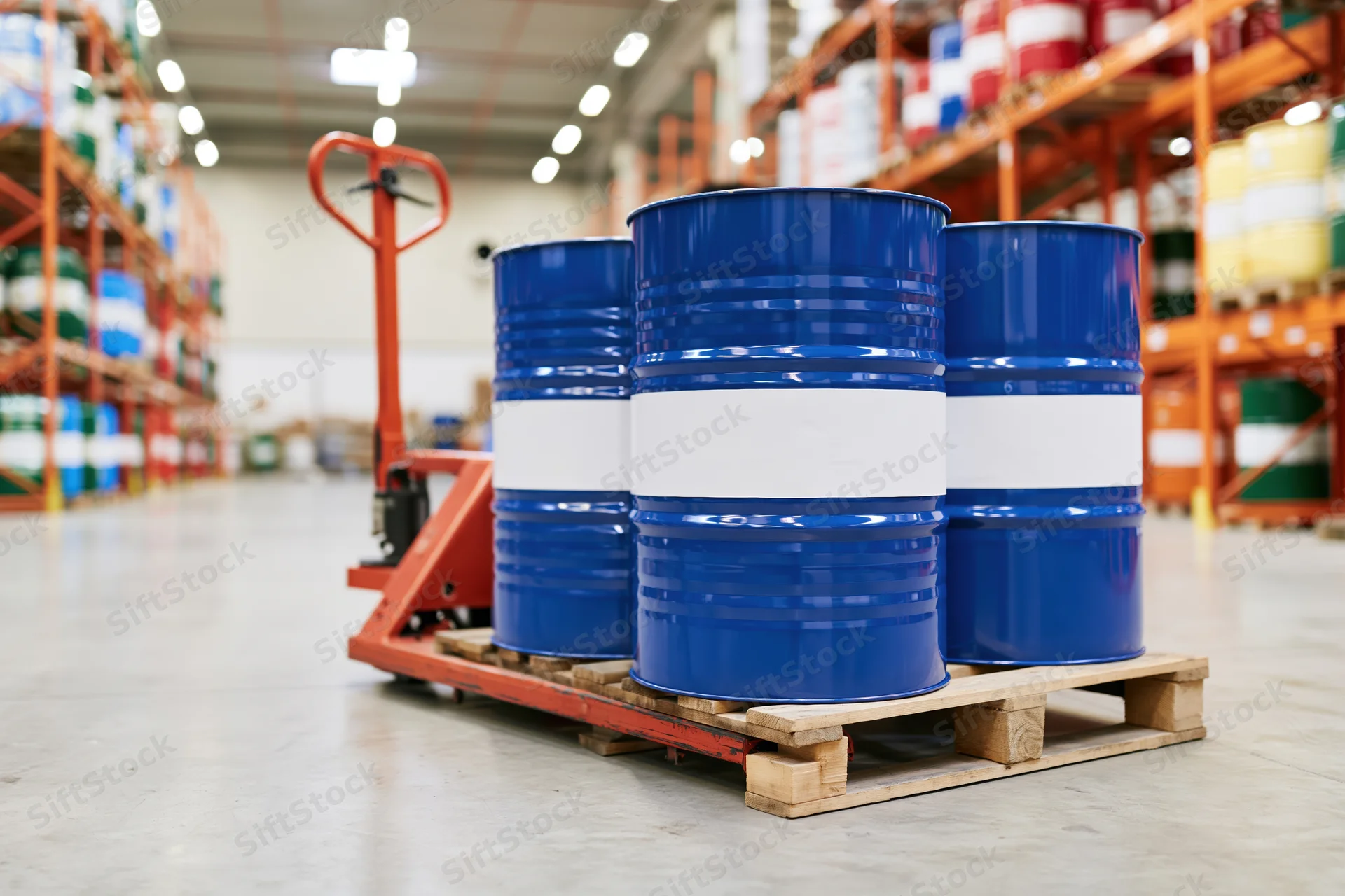 Blue metal industrial drums on wooden pallet in warehouse aisle with forklift and shelving in background