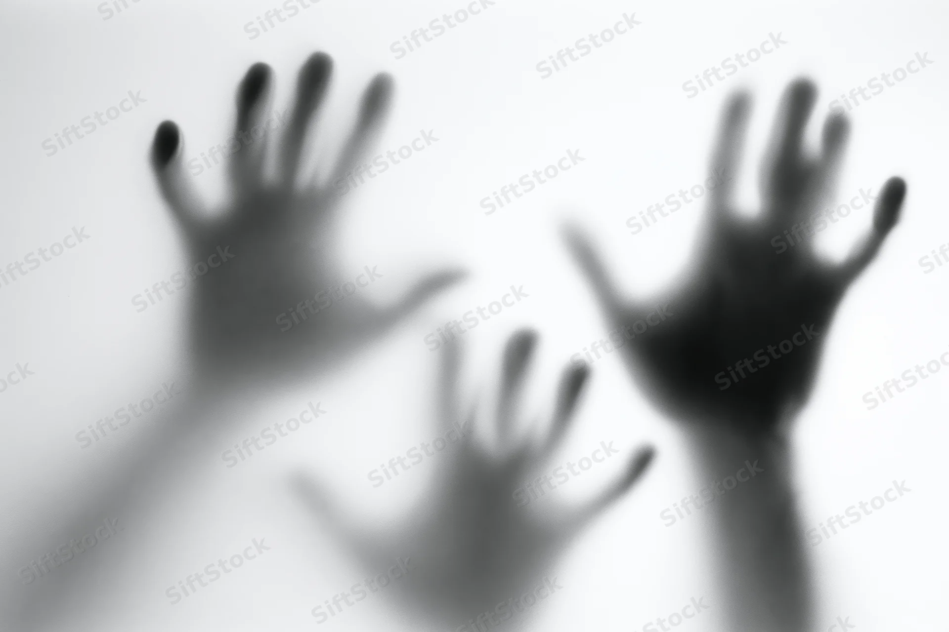 Blurred hands pressing against frosted glass in a white space