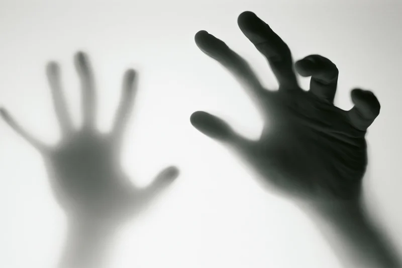 Blurred hands pressing against frosted glass surface