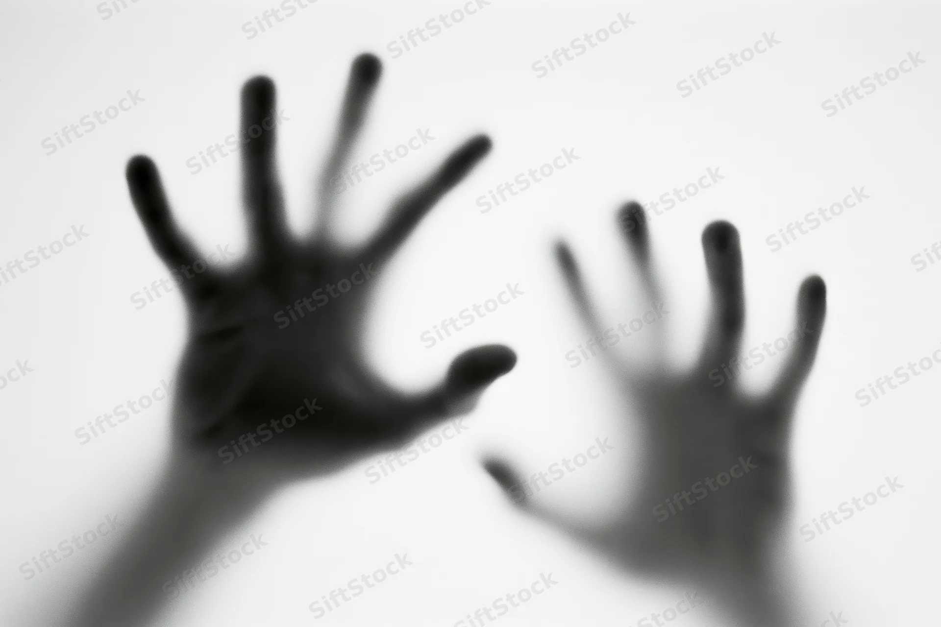 Blurred hands pressing against frosted glass in a white space