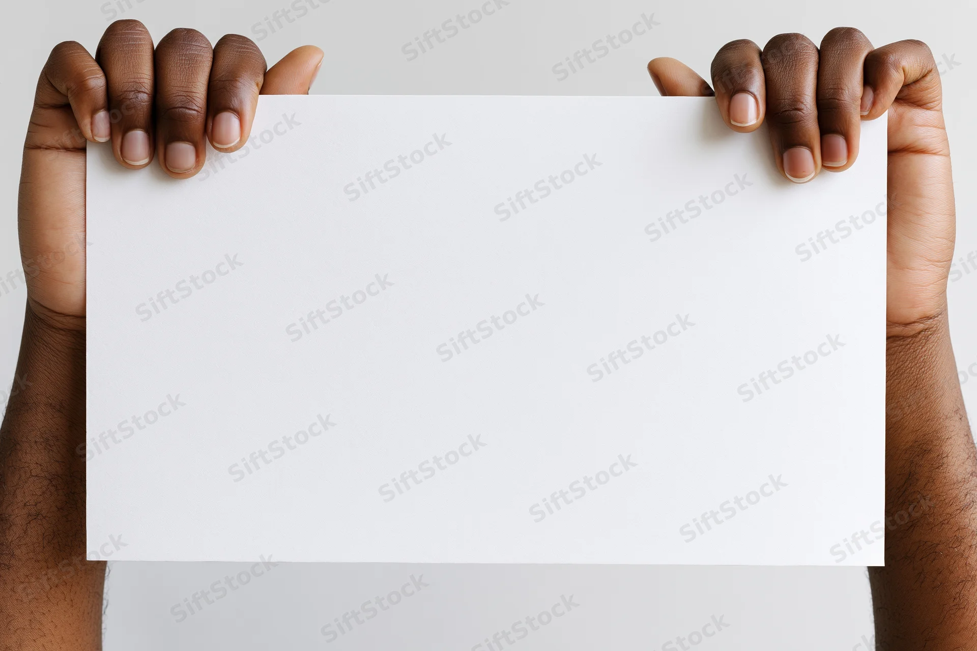 Dark-skinned hands holding blank white paper sheet against plain background