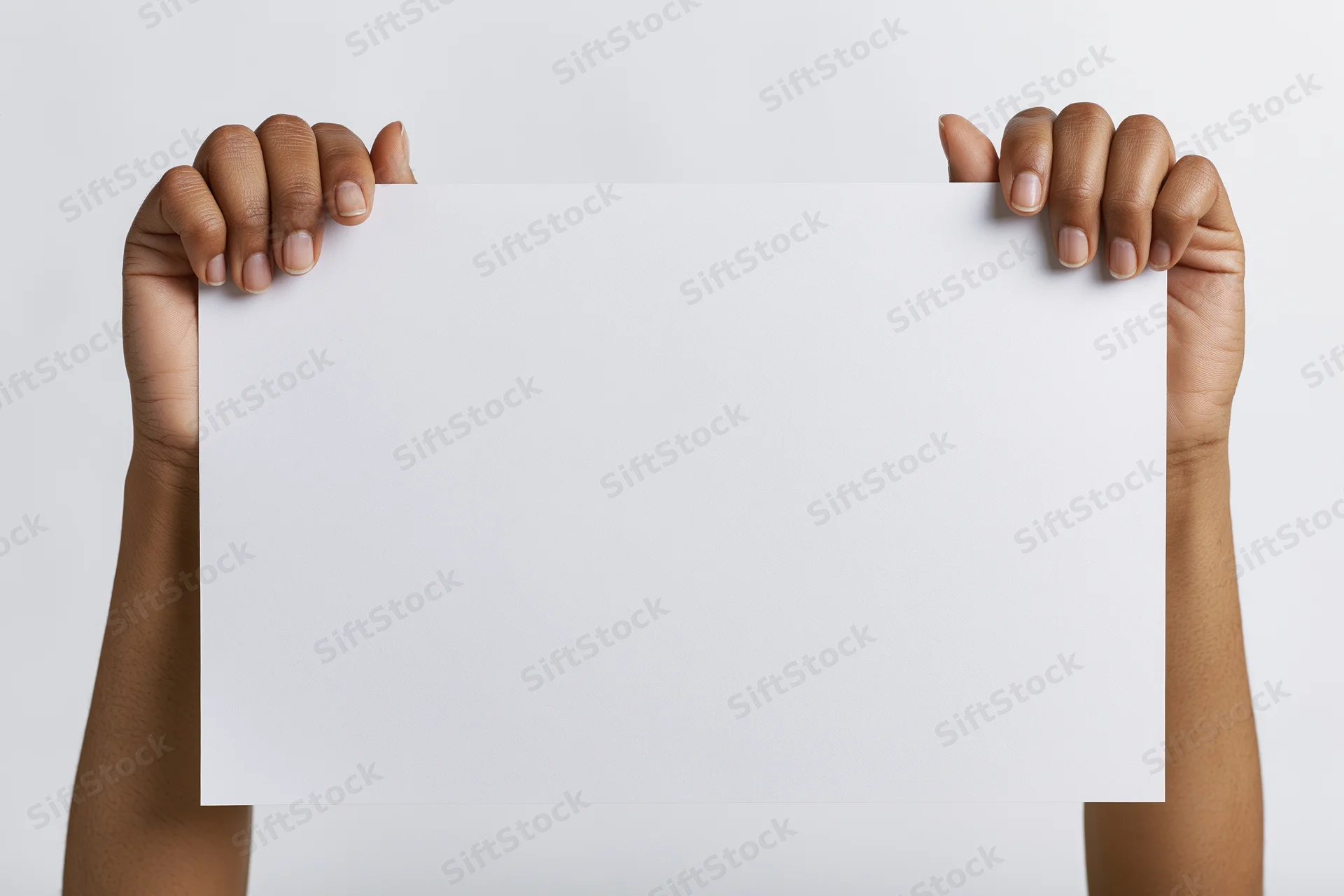 Hands holding blank white paper against plain background