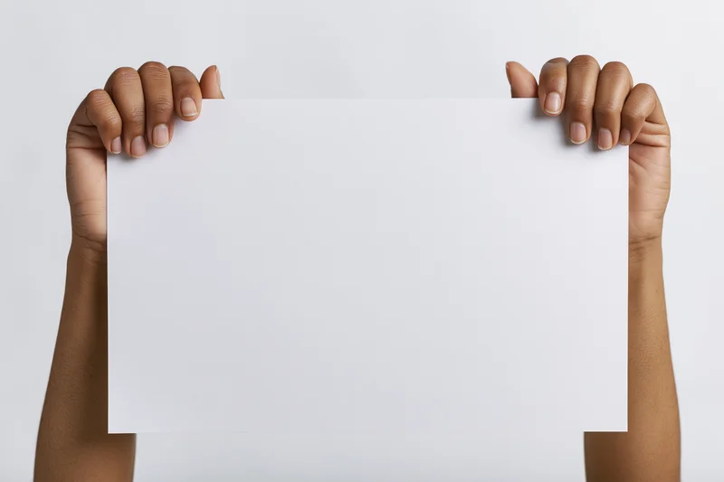 Hands holding blank white paper against plain background
