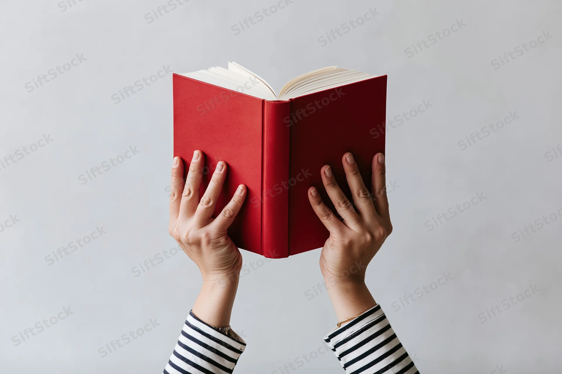 Hands holding open red hardcover book above white background