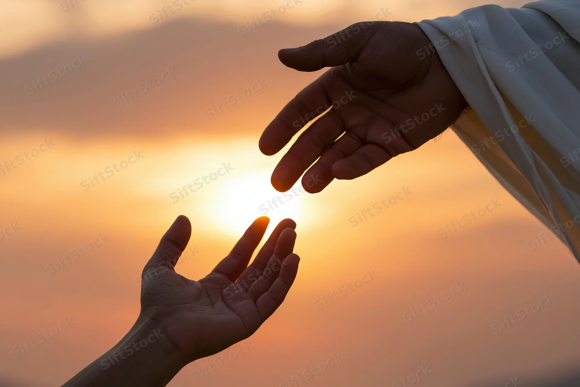 Two hands reaching toward each other in silhouette against a sunset sky