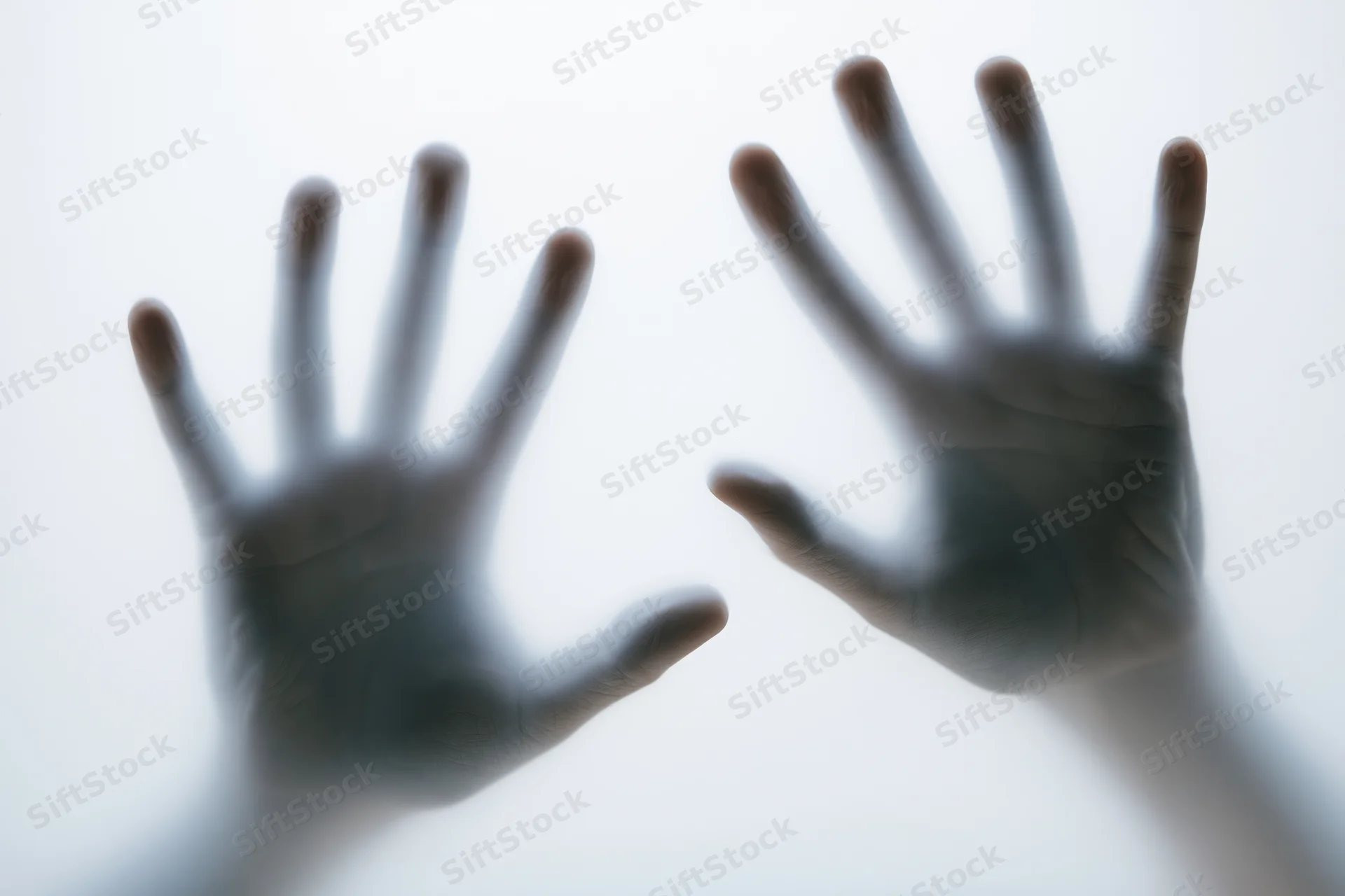 Two hands pressed against frosted glass