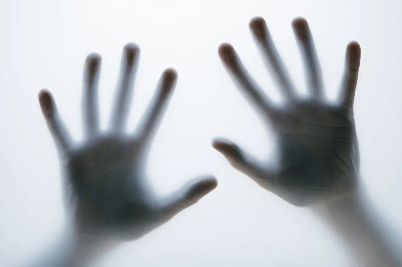 Two hands pressed against frosted glass
