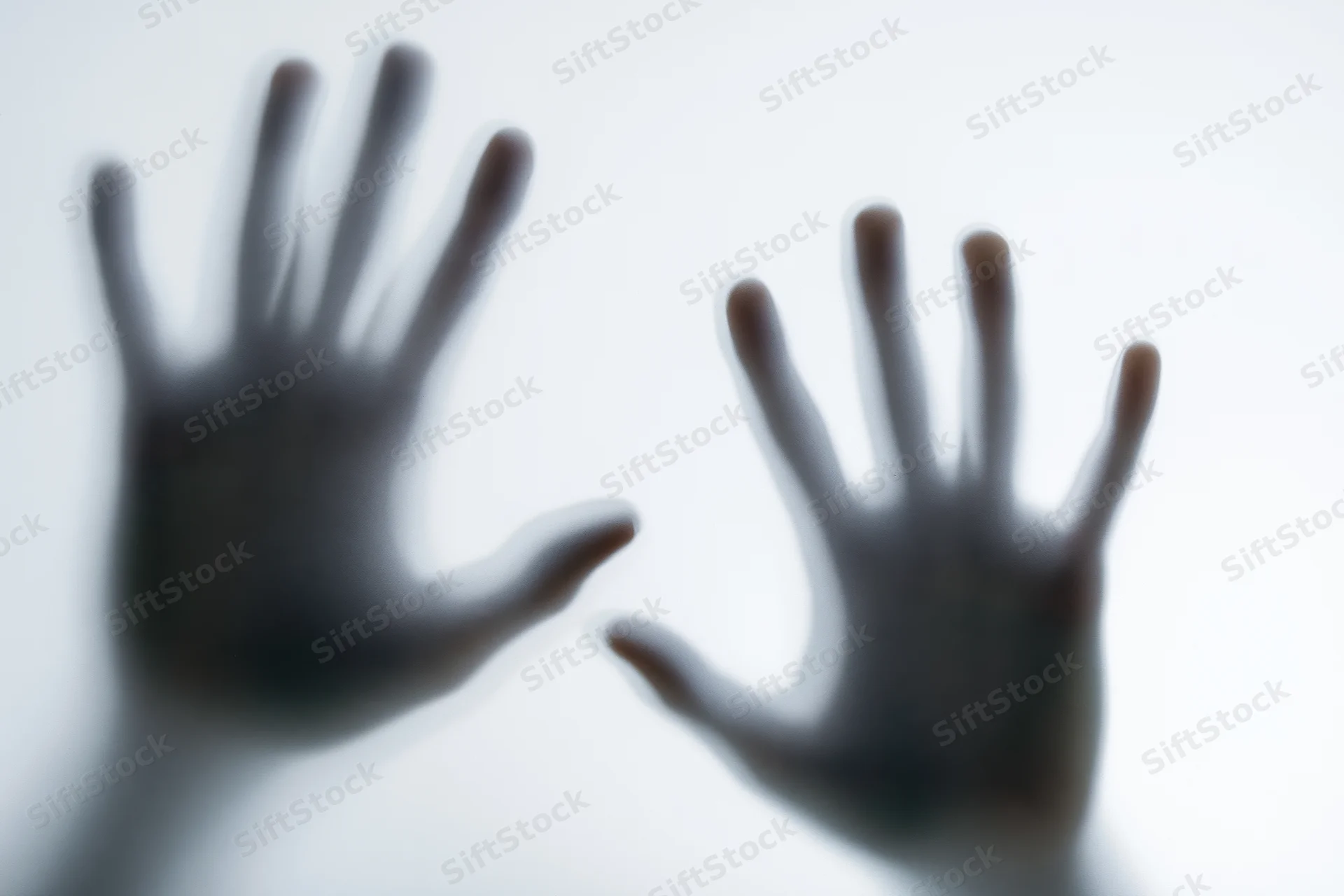 Two hands pressed against frosted glass in a close-up view