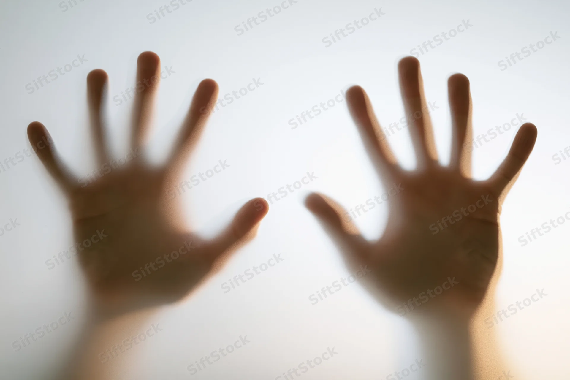 Two human hands pressed flat against frosted glass from behind