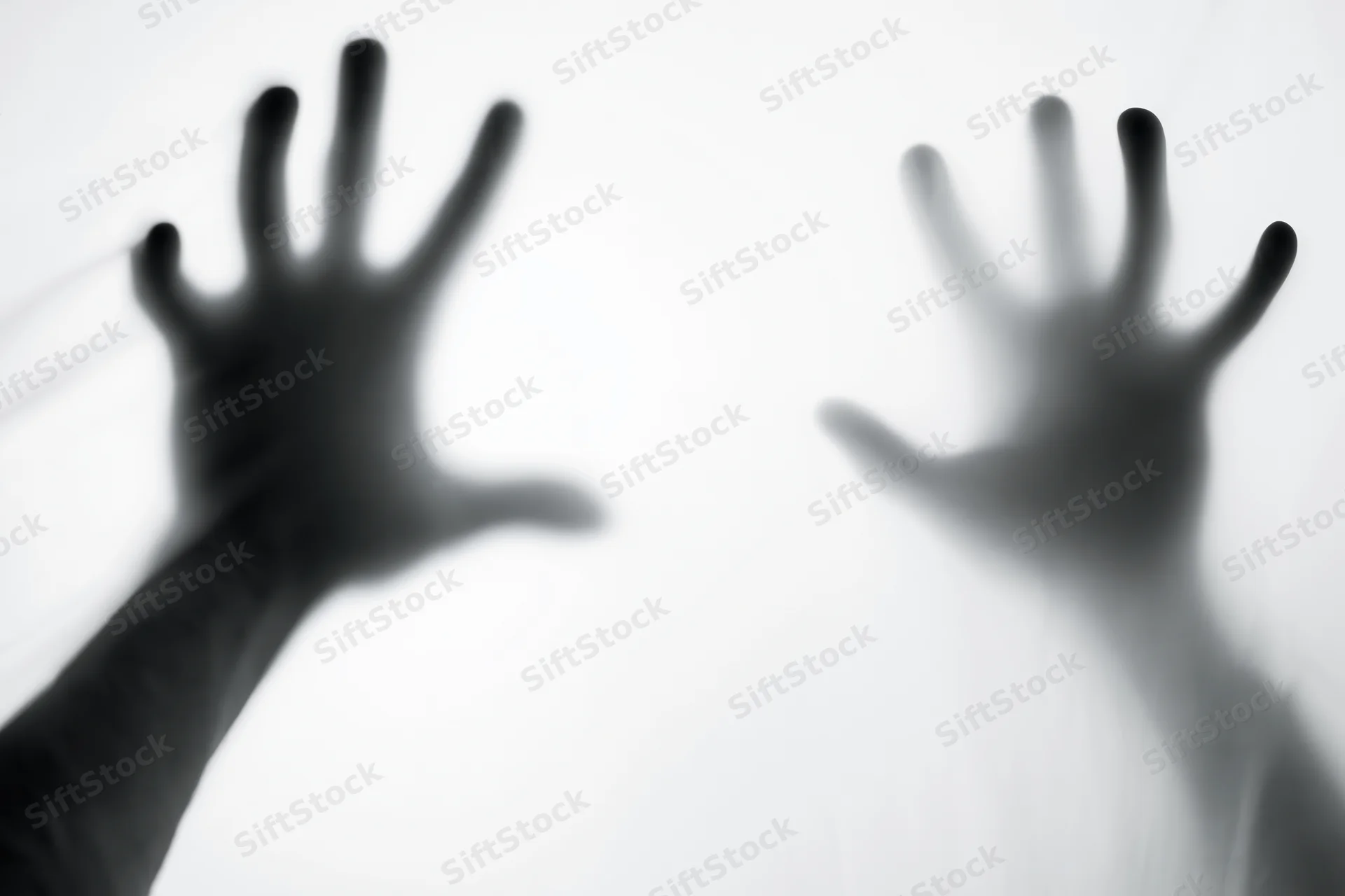 Two hands pressed against frosted glass in a blurred silhouette